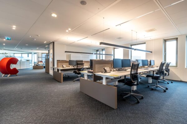 Modern kantoorinterieur aan de Fascinatio Boulevard met open werkplekken en een opvallende rode C-vormige stoel.